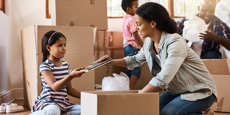 Woman and daughter packing books into a box